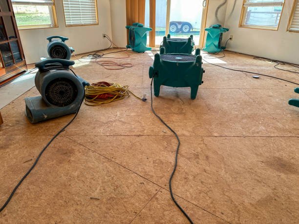 A room filled with water damage restoration equipment surrounded by standing water on the floor.