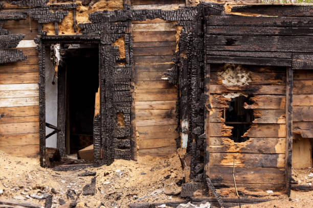 Interior of a fire-damaged room with a broken window and door, highlighting the need for restoration and repair.