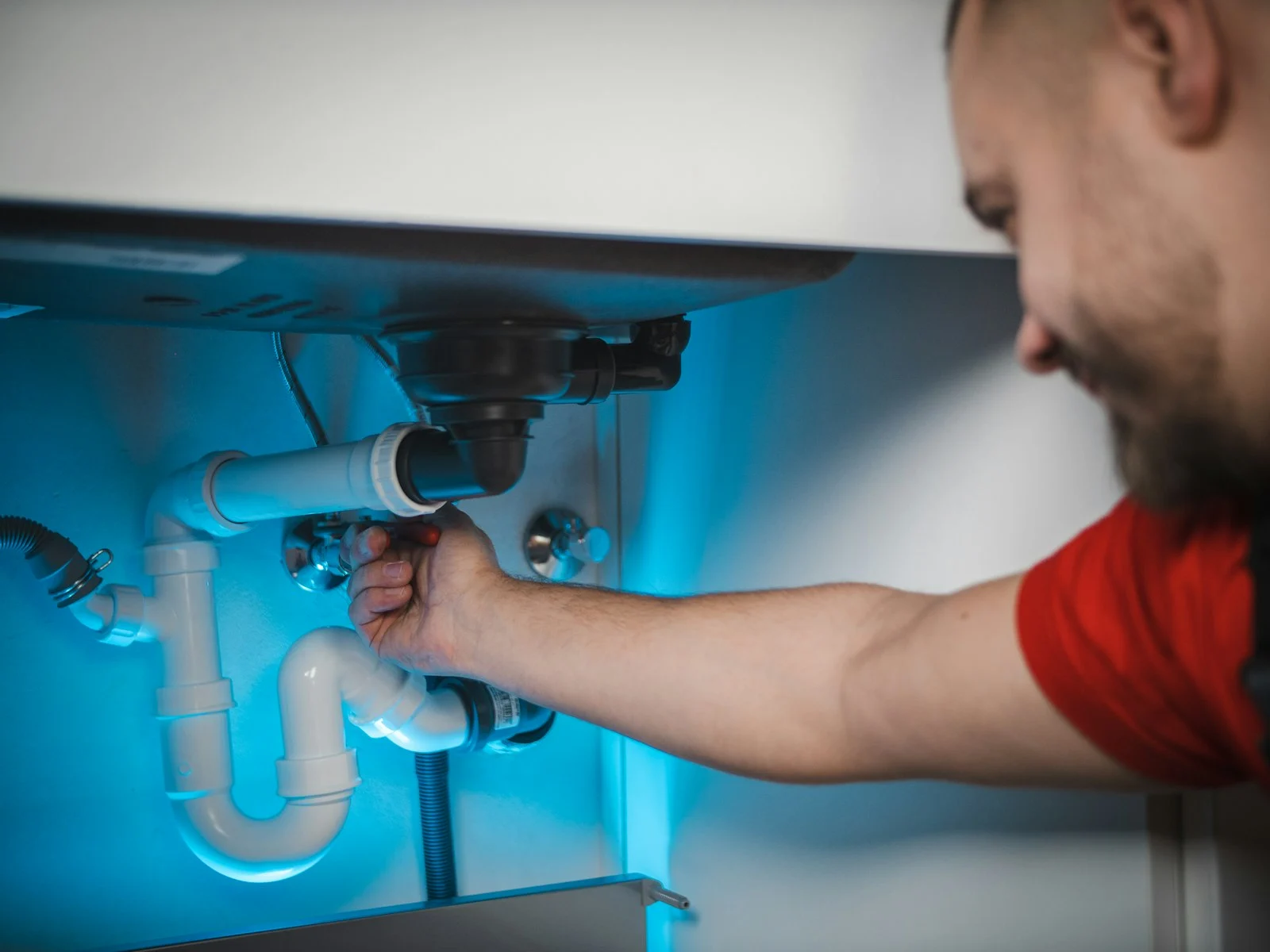 Technician repairing a leaking pipe inside a wall